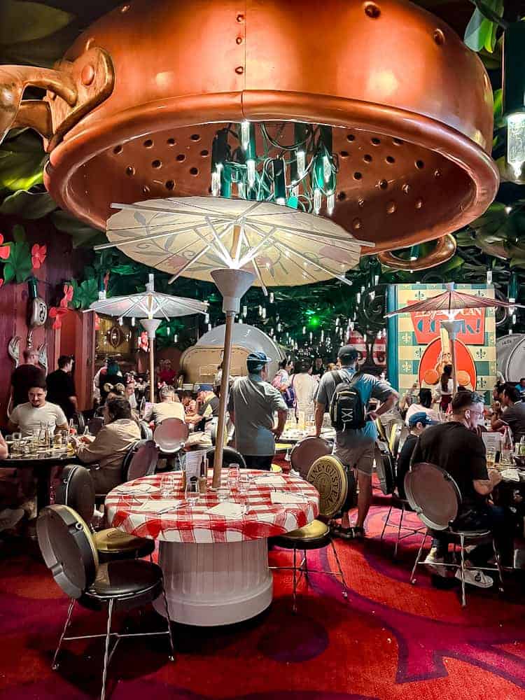 Wide view of Bistrot Chez Rémy dining room with oversized décor and colander chandelier