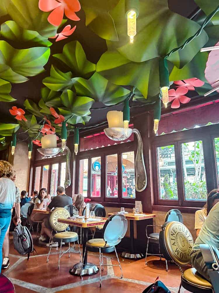 Interior of Bistrot Chez Rémy at Disneyland Paris with giant leaves and oversized spoon lights hanging from the ceiling