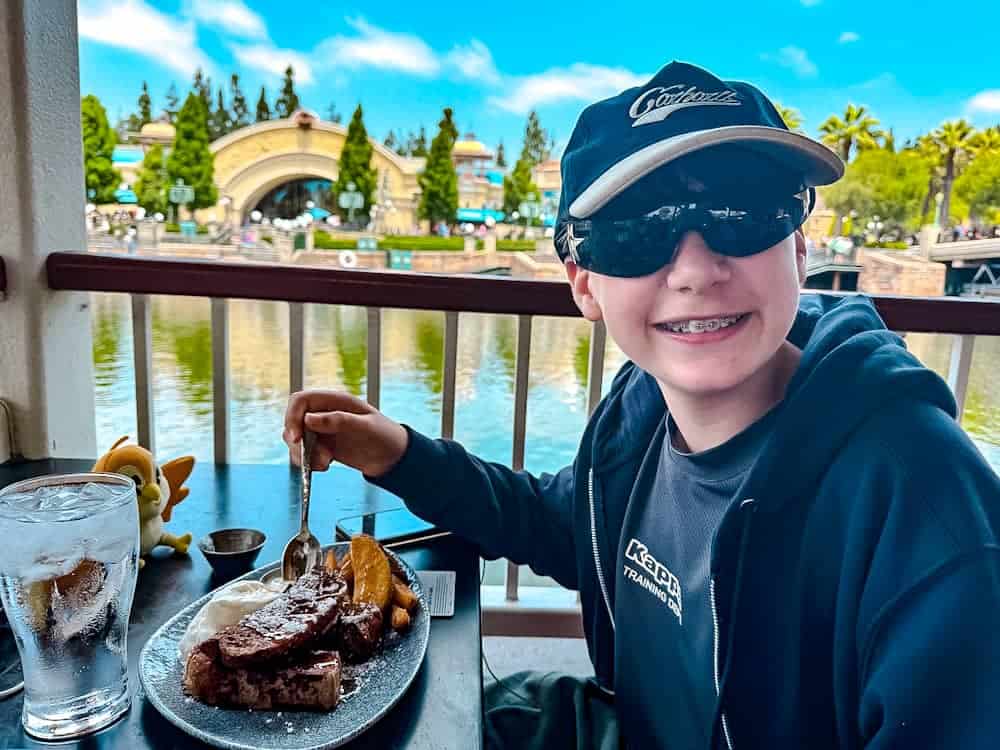 Boy enjoying the kids’ French toast at Lamplight Lounge, Pixar Pier — one of the tastiest Disneyland California food options for children.