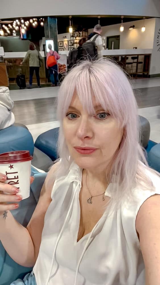 Traveller holding a coffee while waiting at the airport lounge, illustrating delays during the French Air Traffic Control Strike September 2025.