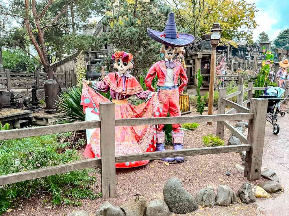 Halloween atmosphere in Frontierland at Disneyland Paris with skeleton performers in colourful Día de los Muertos-inspired costumes near Phantom Manor.