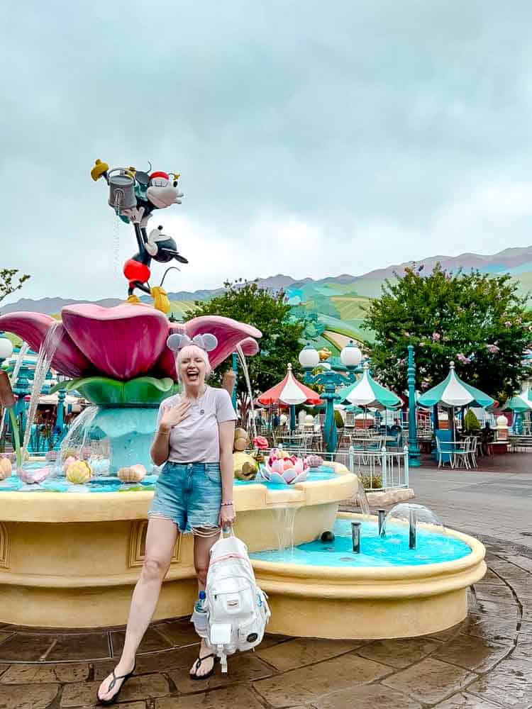 Disney blogger Carrie-Anne in front of a colourful Toontown fountain at Disneyland California with Mickey statue, captured on our 3-Day Disneyland California Itinerary adventure.