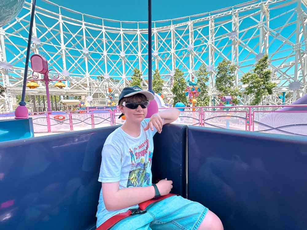 Boy sitting inside a pastel ride gondola on Emotional Whirlwind at Pixar Pier, Disney California Adventure.