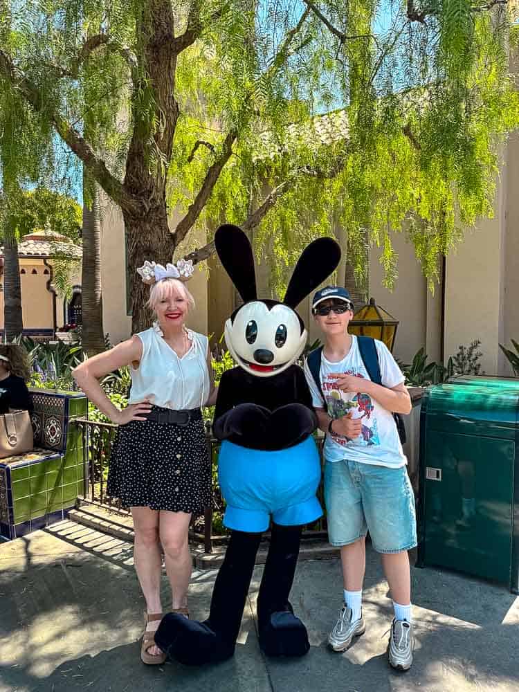 Family posing with Oswald the Lucky Rabbit character meet at Disney California Adventure.