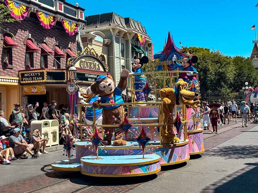 Mickey, Minnie, Pluto, and Duffy riding a colourful Celebrate! Happy Parade float on Main Street at Disneyland California.