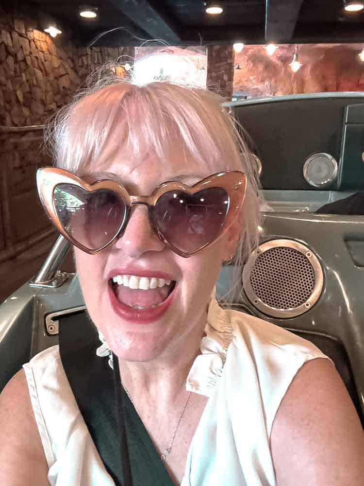 Woman taking a selfie inside the Radiator Springs Racers ride vehicle, smiling before the adventure begins.