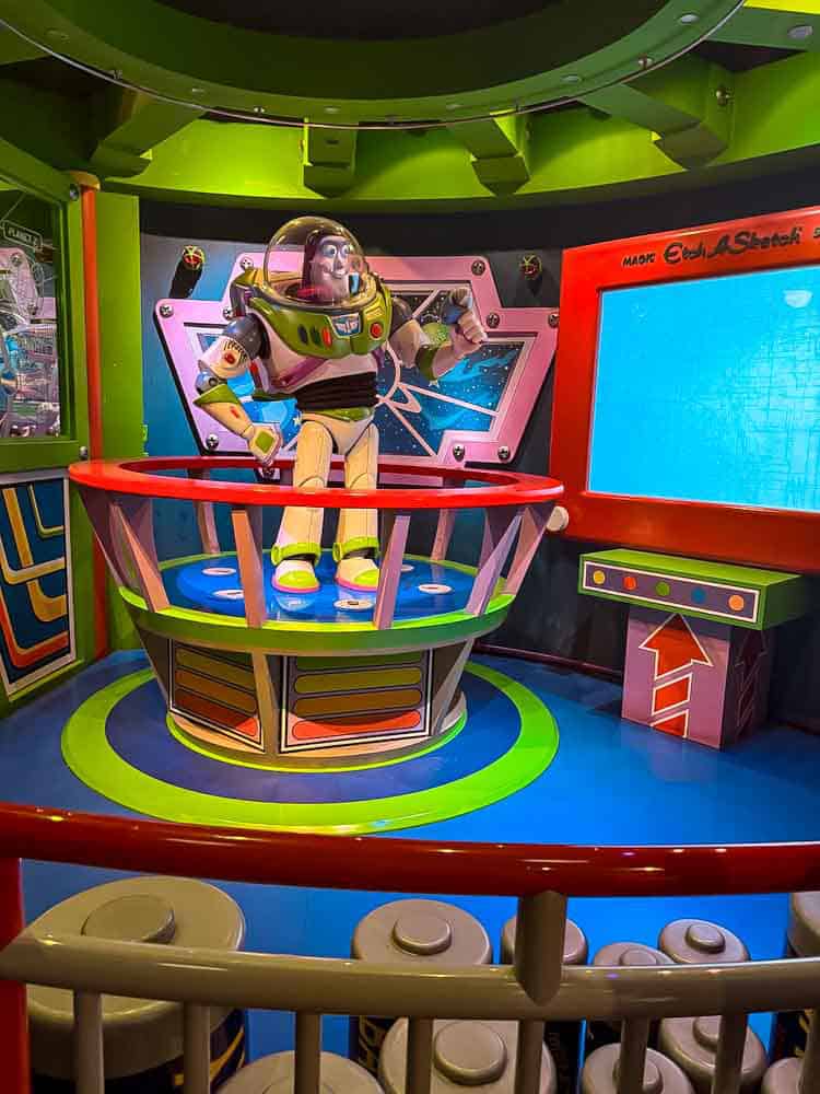 Buzz Lightyear animatronic greeting guests inside the colourful Astro Blasters queue at Disneyland Park.