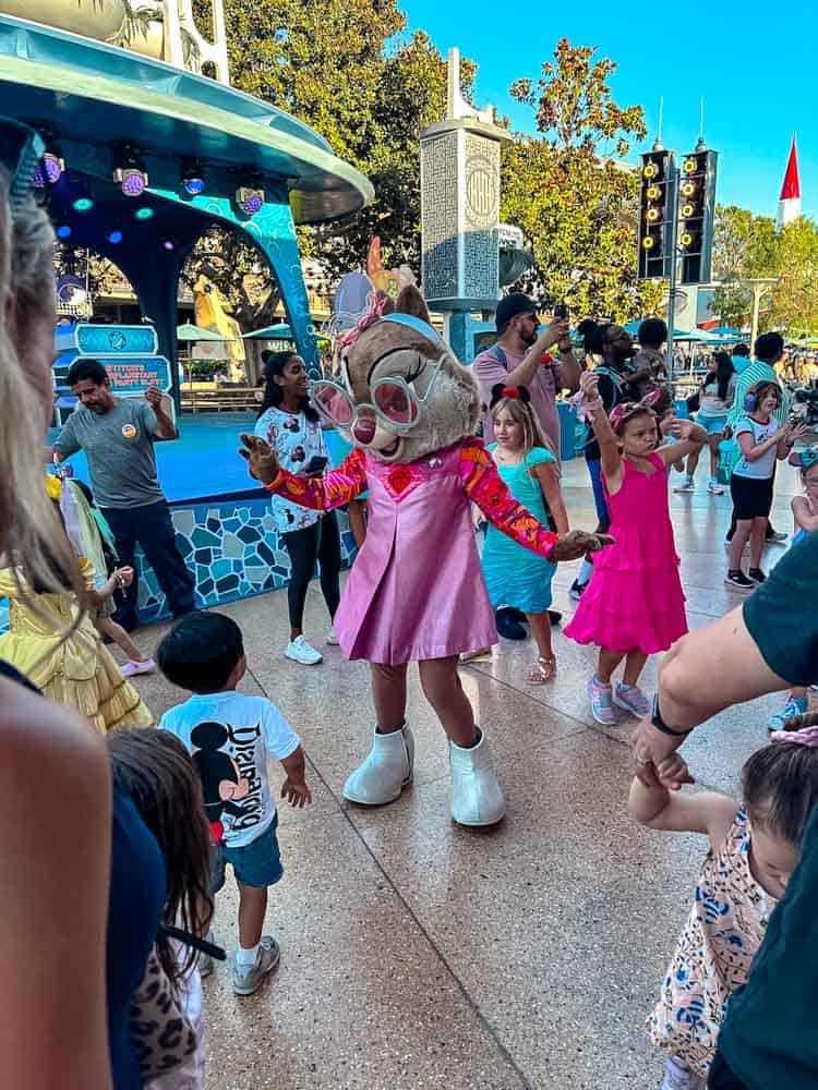 Clarice the chipmunk in a pink dress dancing with children during a spontaneous Tomorrowland dance party at Disneyland California.