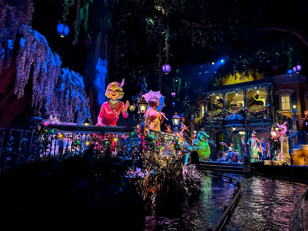 Lively Mardi Gras scene with animatronics and bright decorations inside Tiana’s Bayou Adventure at Disneyland California.