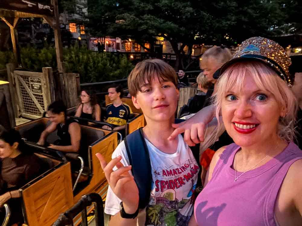 Smiling mum and son in a ride vehicle on Big Thunder Mountain Railroad at Disneyland California, excited for the wild train ride.