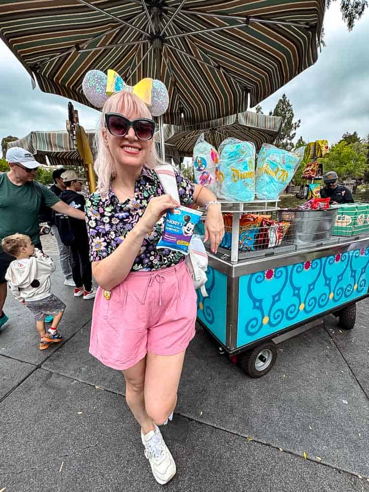 Holding a Mickey ice cream sandwich at a Disneyland snack cart during our 3-Day Disneyland California Itinerary.