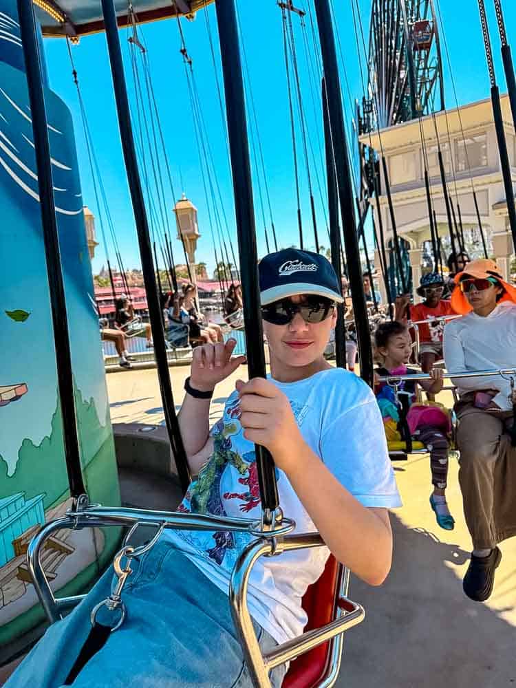 Boy enjoying Silly Symphony Swings at Disney California Adventure, soaring above Pixar Pier with the fun of a classic swing ride.