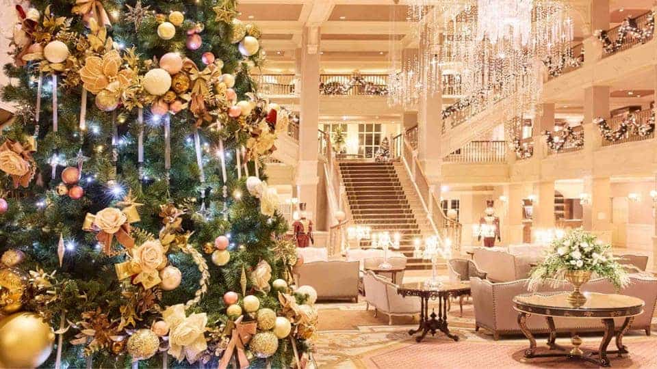 Elegant Disneyland Paris Christmas 2025 decorations at Disneyland Hotel lobby, with golden Christmas tree and chandeliers.