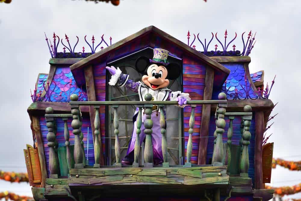 Mickey Mouse in a purple costume standing on the Illusion Manor float during Halloween at Disneyland Paris 2025.