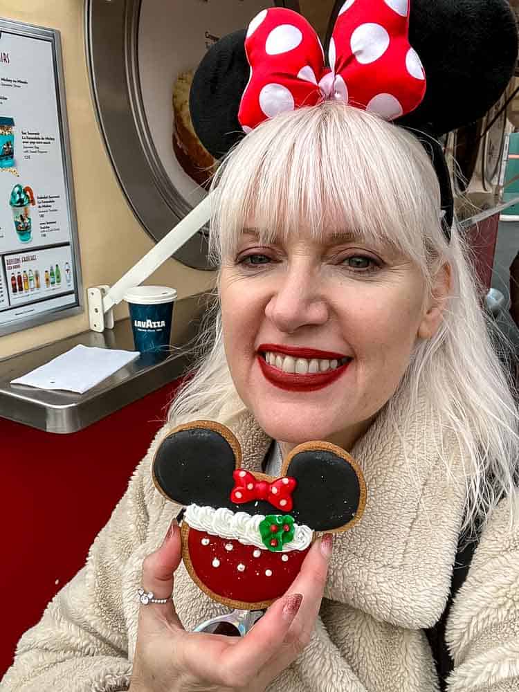 Disneyland Paris blogger Carrie-Anne Hall holding Minnie Mouse Christmas cookie at Disneyland Paris during the December season.