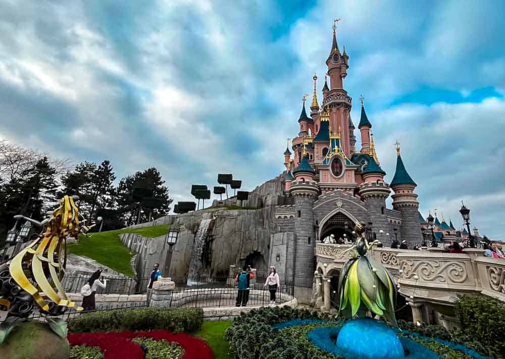 Sleeping Beauty Castle at Disneyland Paris surrounded by winter flowers during the Christmas season.