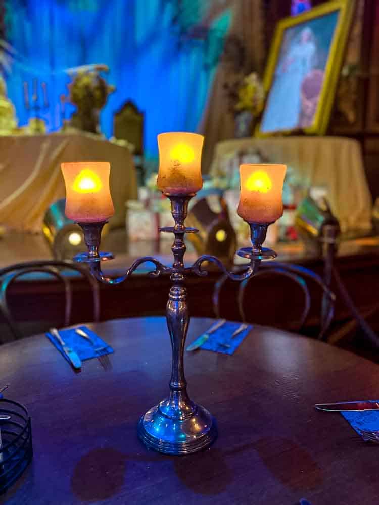 Candelabra centerpiece glowing on a dark wooden table inside the Unlucky Nugget Saloon during Disneyland Paris Halloween 2025.
