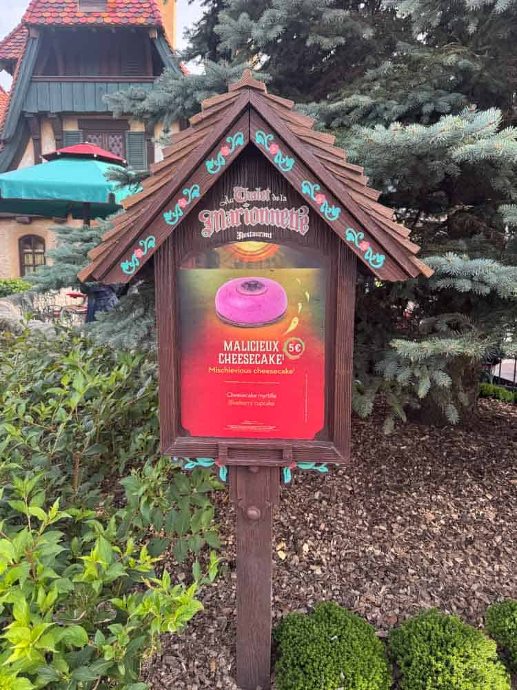 Sign for the Malicious Cheesecake Halloween snack outside Au Chalet de la Marionnette at Disneyland Paris Halloween 2025