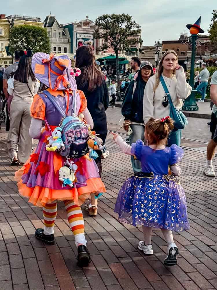 Two children dressed in Halloween dresses walk down Main Street at the Disney Halloween Festival Disneyland Paris.