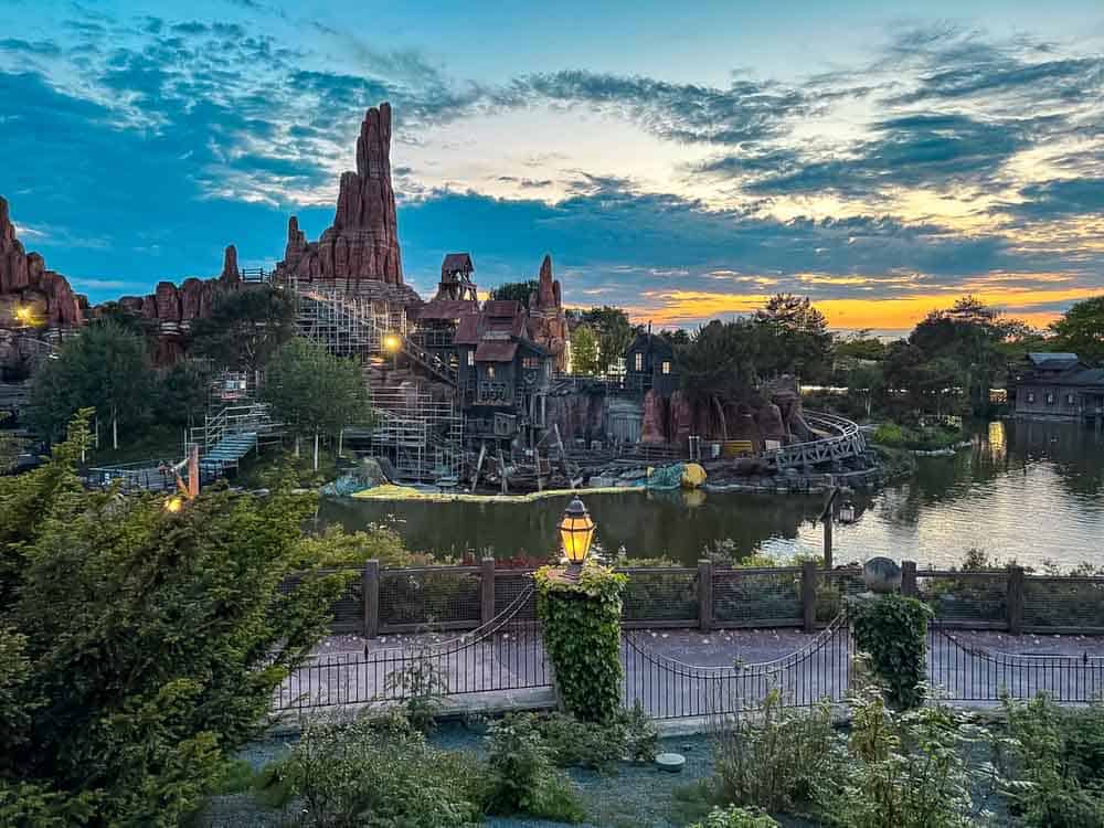 Big Thunder Mountain in Disneyland Paris at sunset, partly surrounded by scaffolding and a cloudy sky