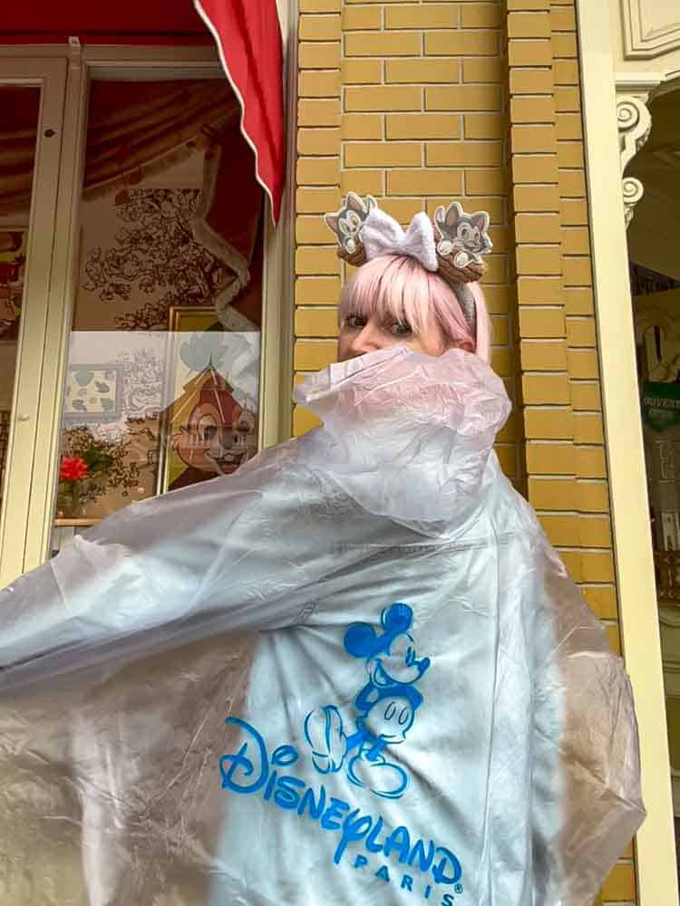Back view of the official Disneyland Paris rain poncho with blue Mickey logo, worn during a wet park day.