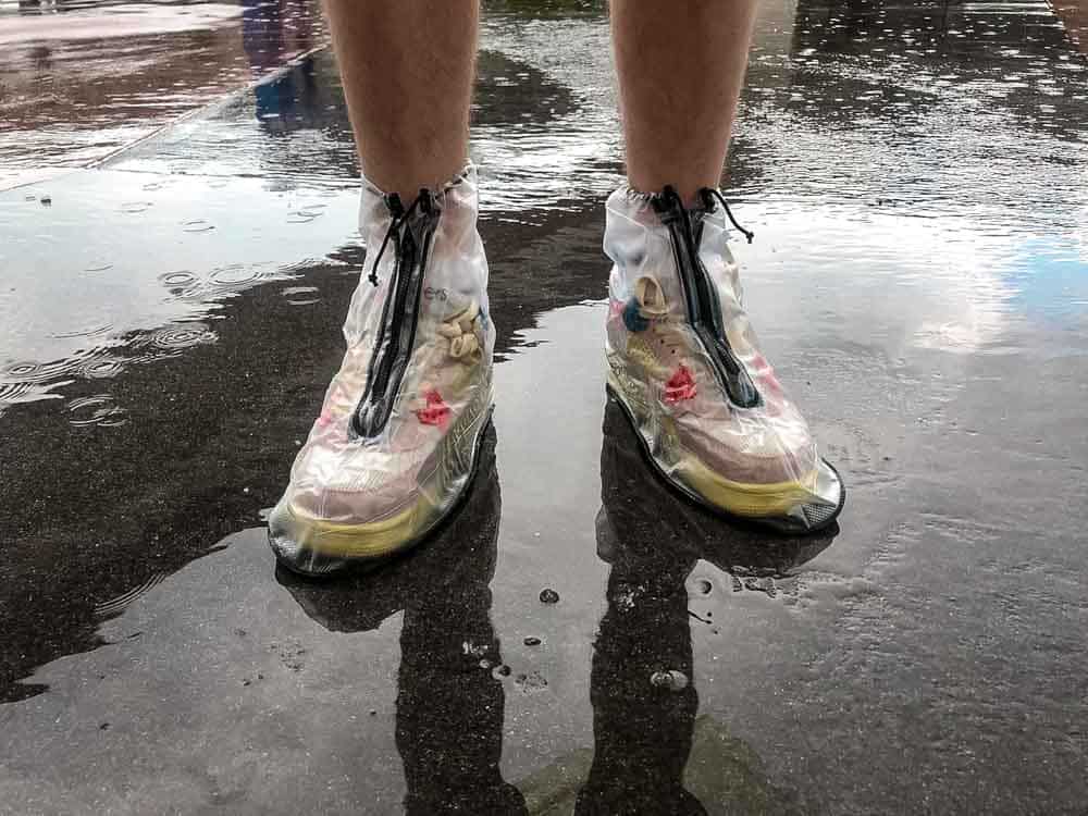 Close-up of plastic shoe covers protecting trainers while standing in a puddle at Disneyland Paris during a rainy day.