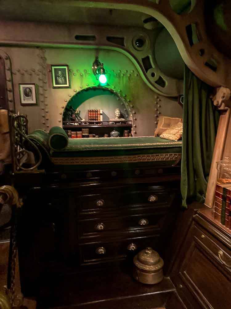 Captain Nemo’s elegant cabin with a green glow and antique furniture in Les Mystères du Nautilus, perfect for escaping the rain at Disneyland Paris.