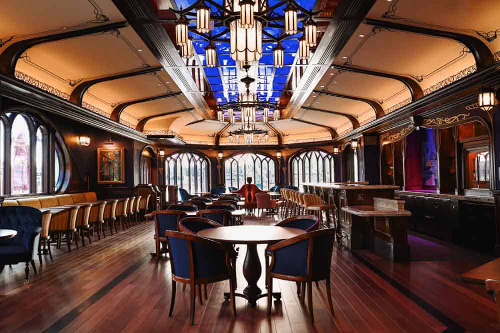 Symmetrical view inside the Regal View Lounge Disneyland Paris showing royal blue tones, elegant ceiling lights and lakeside windows.