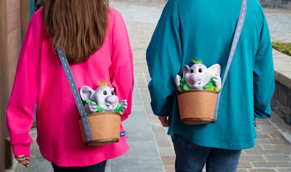 Two guests wearing troll Runa from World of Frozen bags while walking through the village area of World of Frozen at Disneyland Paris.