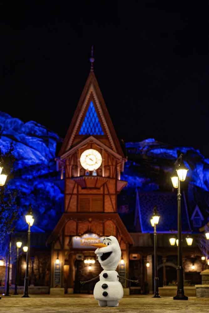 The Robotic Olaf for Disneyland Paris posing in Arendelle at night with blue mountain lighting.