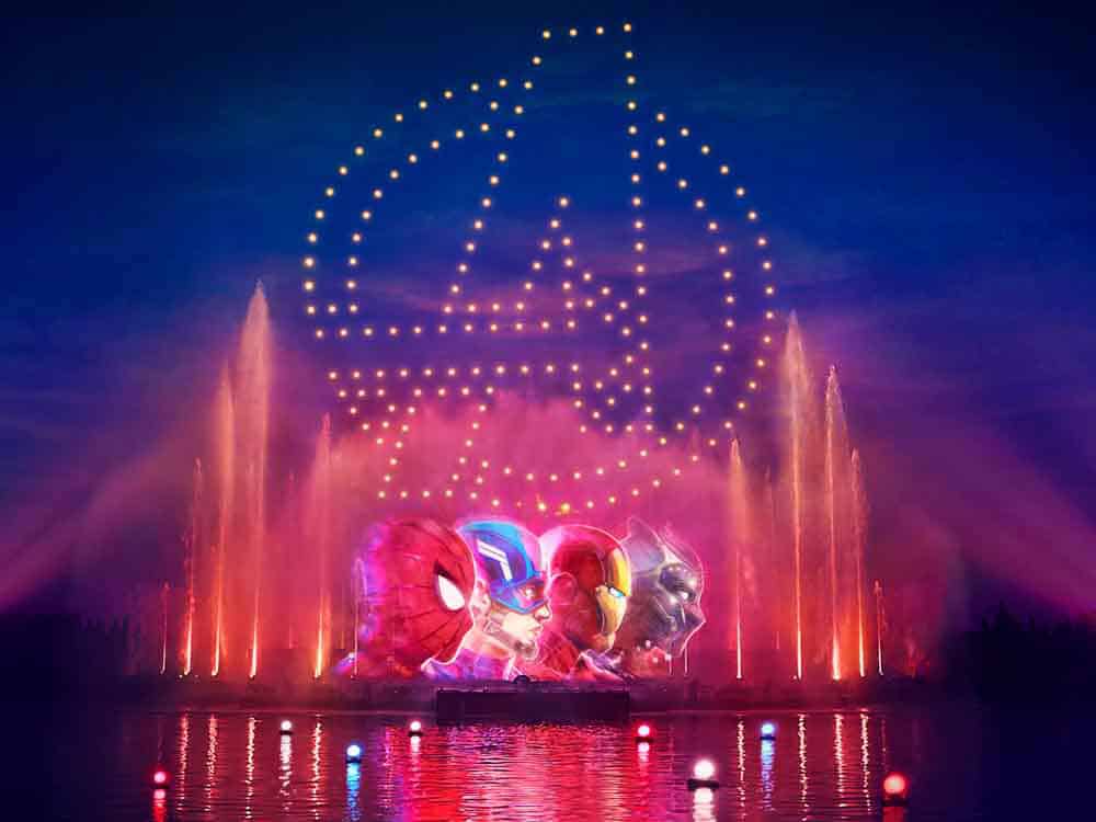 Nighttime view of Disney Cascade of Lights featuring Avengers projections, colourful fountains and drone choreography over Adventure Bay at Disneyland Paris.