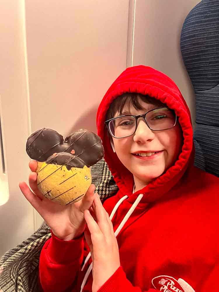 Boy wearing warm winter clothing while enjoying Mickey cookie snack at Disneyland Paris in February