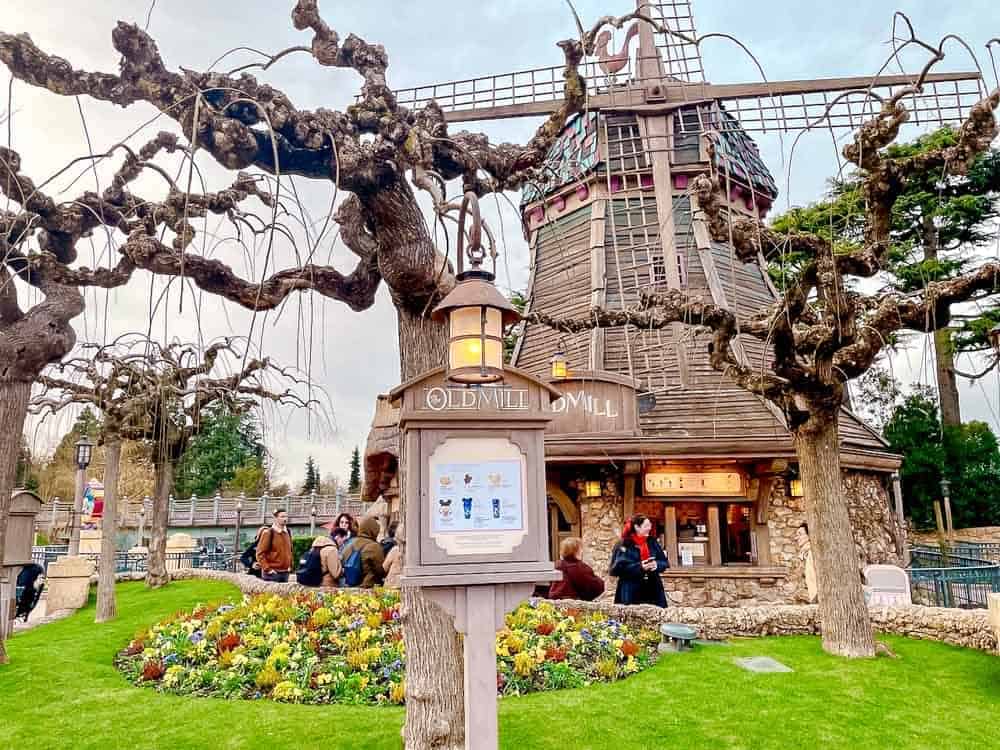 The Old Mill snack stand at Disneyland Paris in March, surrounded by early spring flowers and leafless trees