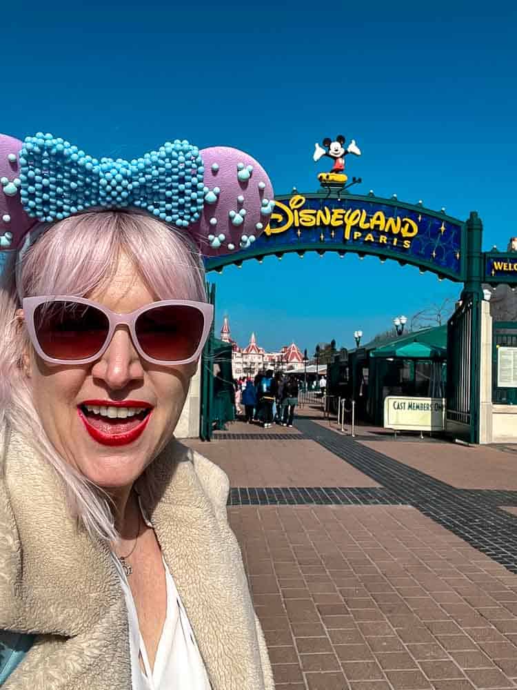 Arriving at Disneyland Paris in March at the park entrance, wearing Minnie ears and sunglasses on a bright spring day