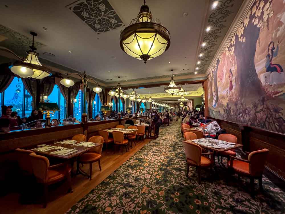 Elegant interior of Regal View Restaurant at Disneyland Paris with mural walls and dining tables