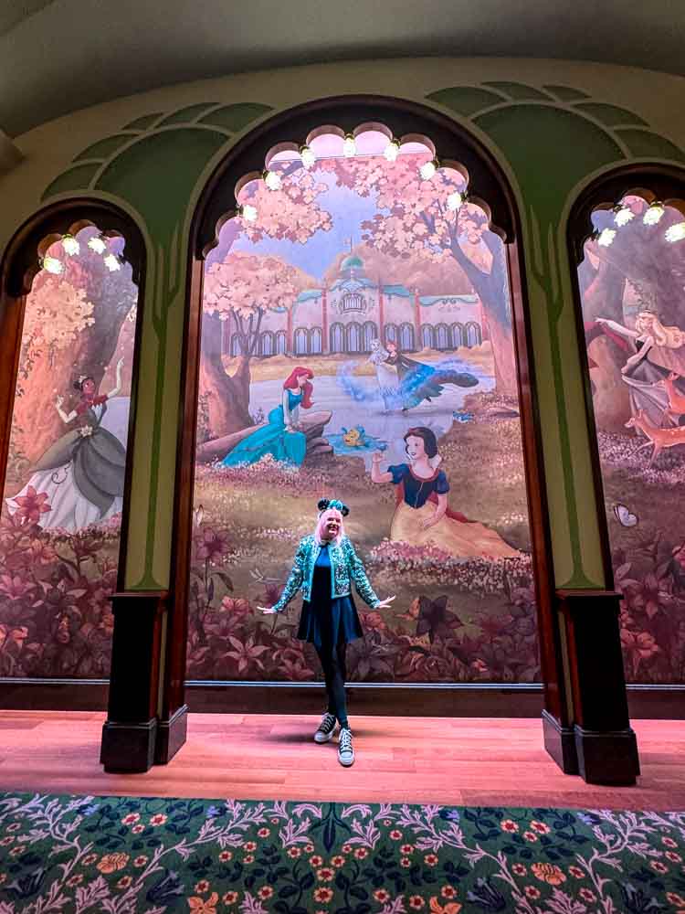 Guest standing in front of decorative mural inside Regal View Restaurant Disney Adventure World