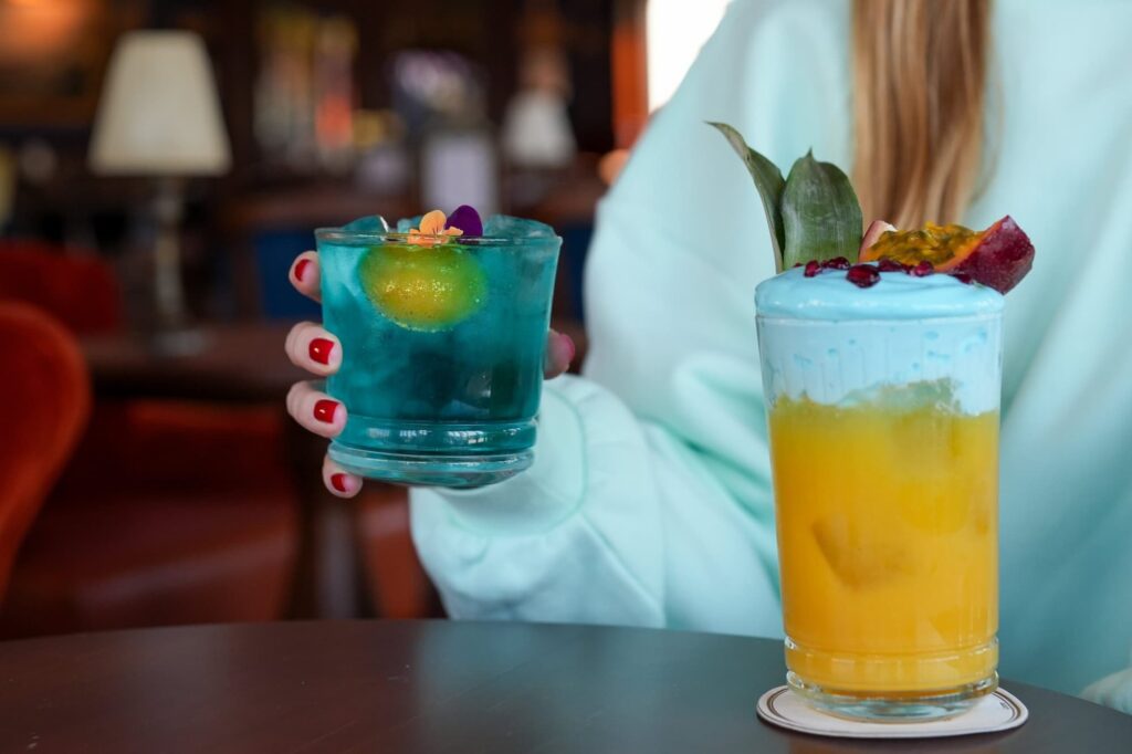 Two colourful cocktails at the Fleur de Lys Bar in Disneyland Hotel, served alongside a fresh fruit garnish platter