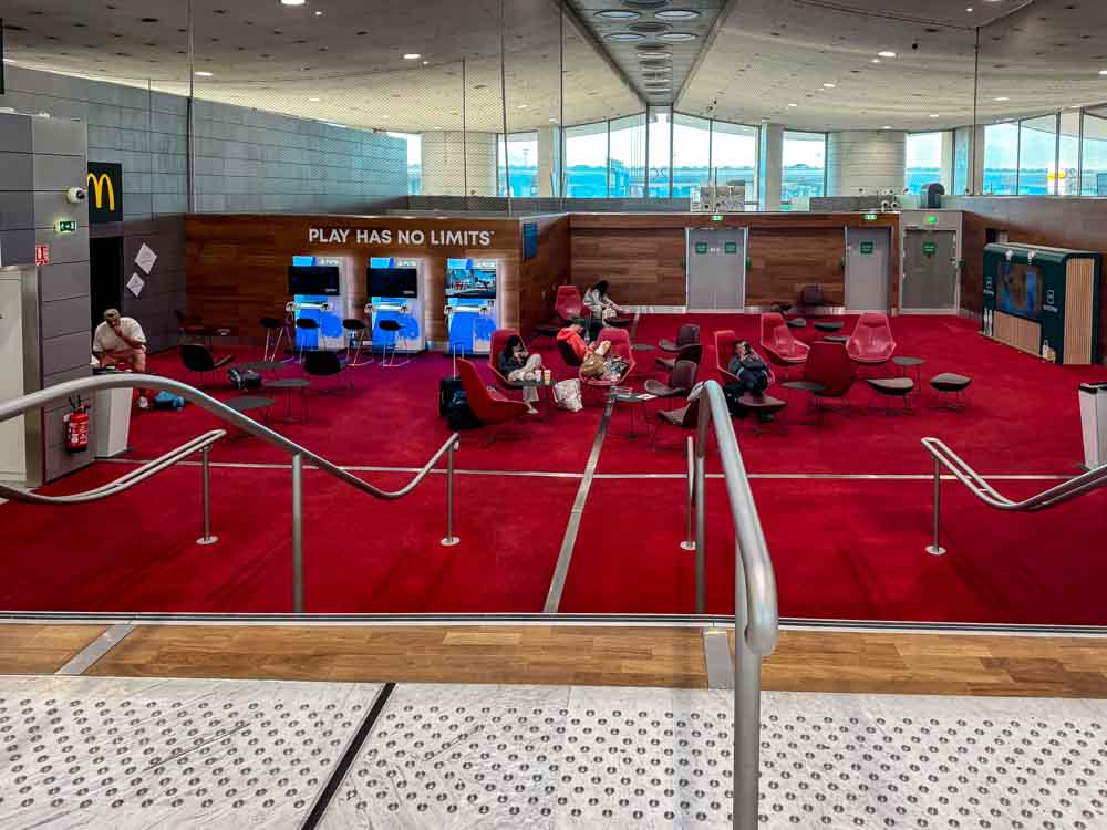 Red seating area with a PlayStation gaming zone in the departure lounge at Charles de Gaulle Airport