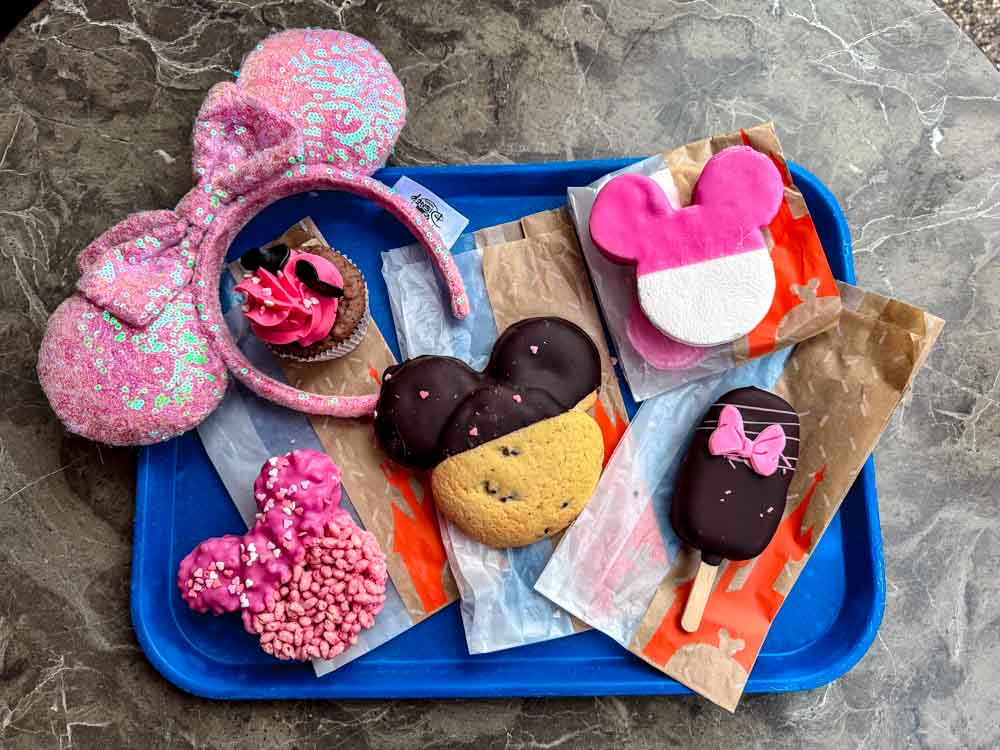 Selection of Minnie and Mickey-shaped chocolate treats, cookies and pink Valentine's snacks displayed on a blue tray at Disneyland Paris.